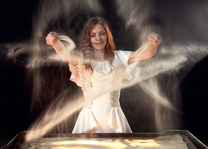 Sand artist tossing sand as it swirls in circular orbits around her during New-Year Eve performance