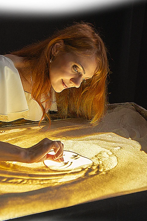 Sand animation artist Daria Tym creating a live sand painting performance.