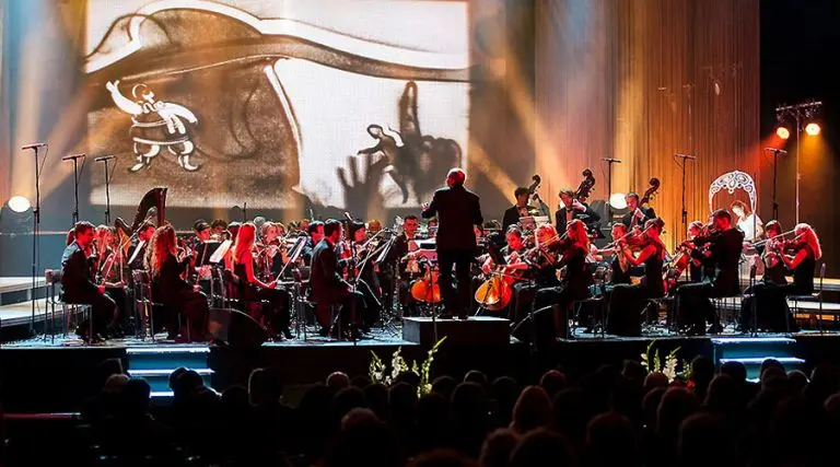 Artist creating a live sand show for corporate events featuring a symphony orchestra performance of Rossini's William Tell for the Swiss Embassy.