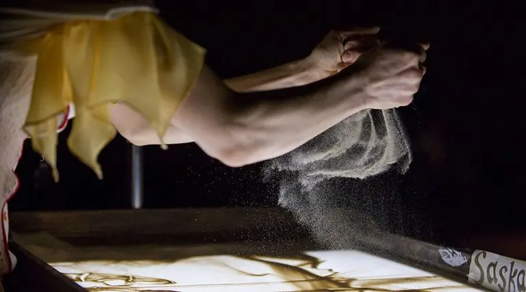 Close-up of an artist's hand creating a live sand show for music concerts during a performance with Lords of the Sound at the Lviv Opera House.